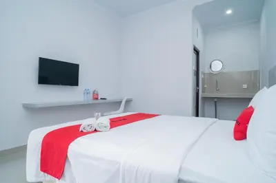 a bedroom with a white bed with a red blanket at RedDoorz @ Jalan Gunung Talang Mahendradatta in Kerobokan