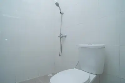 a white bathroom with a shower with a toilet at RedDoorz @ Jalan Gunung Talang Mahendradatta in Kerobokan