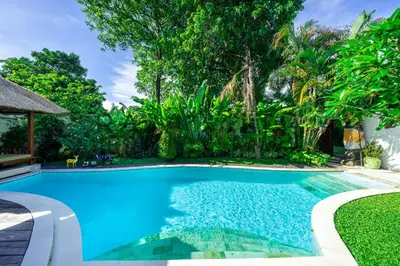a swimming pool in a yard with trees at Villa Kainara Seminyak by RPM in Seminyak