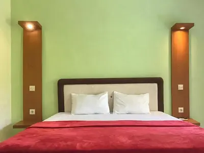 a bed with a red blanket and two pillows at Pondok Mesari Padma Legian RedPartner in Legian