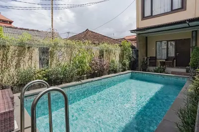 a swimming pool in the backyard of a house at Taxa Uma Guest House in Kuta