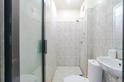 a bathroom with a shower and a toilet and a sink at Taxa Uma Guest House in Kuta