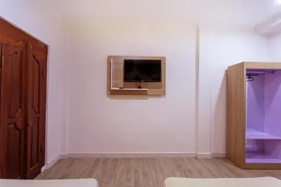 a room with a tv on a white wall at Segara Sadhu Inn Kuta by ecommerceloka in Kuta