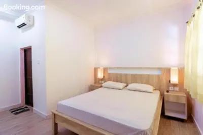a bedroom with a large white bed with two pillows at Segara Sadhu Inn Kuta by ecommerceloka in Kuta