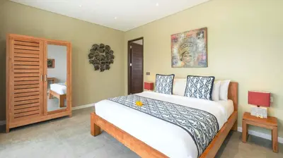 a bedroom with a large bed and a mirror at Villa Nikaia by Villa Finder in Seminyak