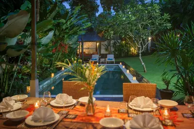 a table set up for a meal next to a pool at Villa Liang by Nagisa Bali in Seminyak