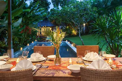 a wooden table with a vase of flowers on it at Villa Liang by Nagisa Bali in Seminyak