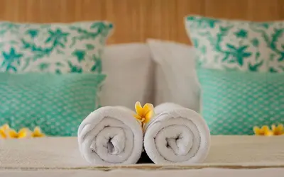a pair of towels with a flower on a bed at The Indies Estate in Sanur
