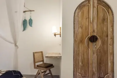 a wooden door in a room with a chair at Madeira Javanese Joglo, Jimbaran in Jimbaran