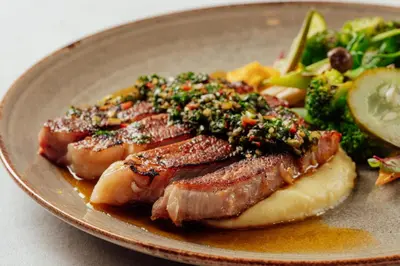 a plate of food with meat and vegetables on it at Monolocale Resort & Spa Seminyak by Ini Vie Hospitality in Seminyak