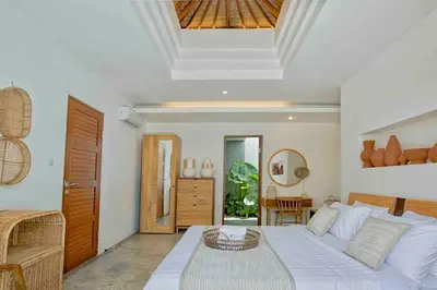 a bedroom with a bed and a table in it at THE MILAGRO VILLA in Canggu
