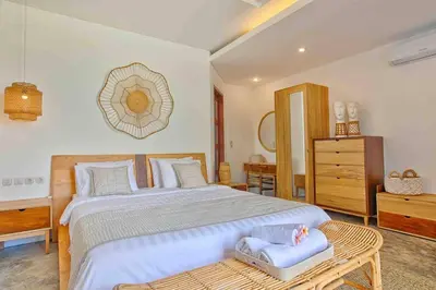 a bedroom with a large bed and a dresser at THE MILAGRO VILLA in Canggu