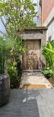 a wooden door with a tree in front of a building at Rumah Hadeka Petitenget in Seminyak