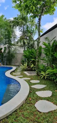 a garden with a walkway next to a swimming pool at Rumah Hadeka Petitenget in Seminyak