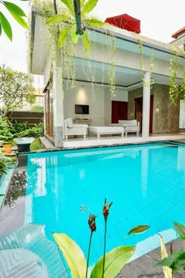 a swimming pool in front of a house at Villa Cleopatra Bali in Sanur