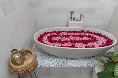 a bath tub filled with pink flowers in a bathroom at Villa Luna Rose in Seminyak