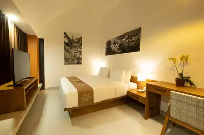a bedroom with a bed and a desk and a television at THE COINS VILLA SEMINYAK in Seminyak