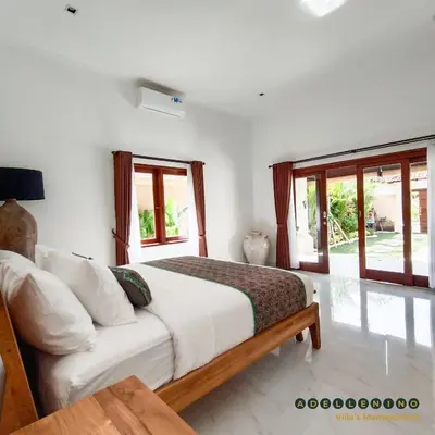 a bedroom with a bed with white walls and windows at CASA LUWIH Newly Renovated 2BR Villa with Private Pool in Seminyak in Seminyak