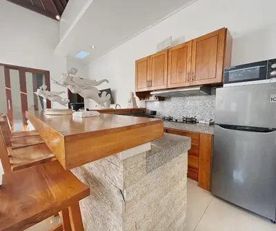 a kitchen with wooden cabinets and a stainless steel refrigerator at CASA BISMA - 3 Bedroom Villa with Pool in LEGIAN in Seminyak