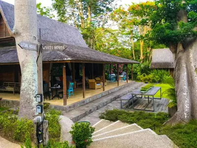 a white house with a sign on a tree at Chanteak Bali - Stone House 1 in Jimbaran