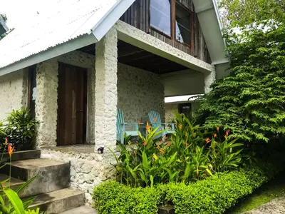 a house with a porch with blue chairs and plants at Chanteak Bali - Stone House 2 in Jimbaran
