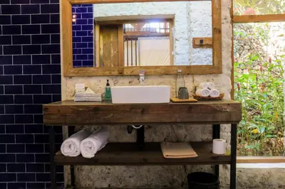 a bathroom with a sink and a mirror and towels at Chanteak Bali - Stone House 3 in Jimbaran
