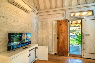 a living room with a tv and a window at Chanteak Bali - Teak House 1 in Jimbaran