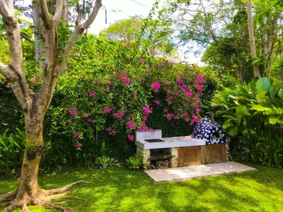 a bench in a garden with pink flowers at Chanteak Bali - Teak House 3 in Jimbaran