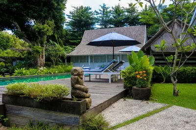 a patio with a bear statue next to a pool at Chanteak Bali - White House 1 in Jimbaran