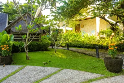 a garden with some plants and trees and a building at Chanteak Bali - White House 1 in Jimbaran