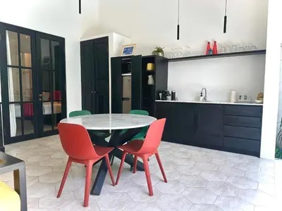 a dining room with a table and chairs and a kitchen at Villa Harris Canggu in Canggu