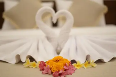 a bed with two swans and flowers on a table at Sunkiest House Canggu in Canggu