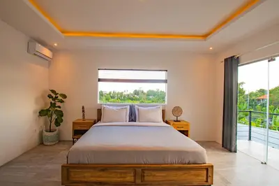 a bedroom with a large bed and a large window at Hedonia Luxury Villas in Seminyak