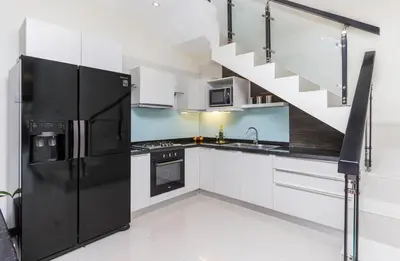 a kitchen with a black refrigerator and a staircase at Villa Cascade in Seminyak