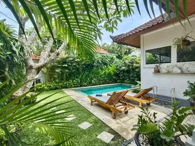 a garden with a pool and two chairs and a house at Villa MONTI - LEGIAN - SEMINYAK - Lovely 2 Bedroom Villa - Great Location ! in Seminyak