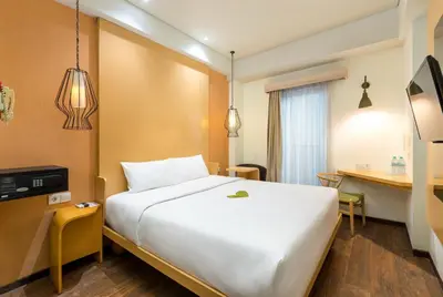a hotel room with a large white bed and a desk at Boss Legian Hotel Powered by Archipelago in Legian