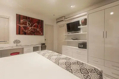 a white bedroom with a bed and a tv at Cozy Bali Apartment in Seminyak