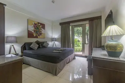 a bedroom with a bed and a table with a lamp at Cozy Bali Apartment in Seminyak