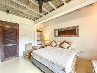 a bedroom with a bed and a chair in it at Istana Semer - Balinese Style Private Event Villa, with Large Pool, Gardens and Cook - Near to Canggu & Seminyak in Kerobokan
