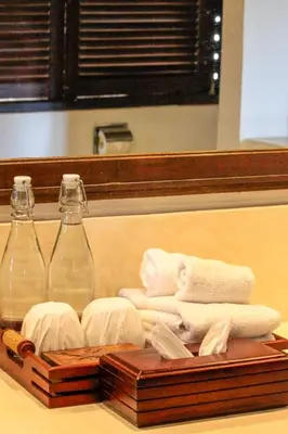a wooden tray with towels and two glass bottles at Istana Semer - Balinese Style Private Event Villa, with Large Pool, Gardens and Cook - Near to Canggu & Seminyak in Kerobokan