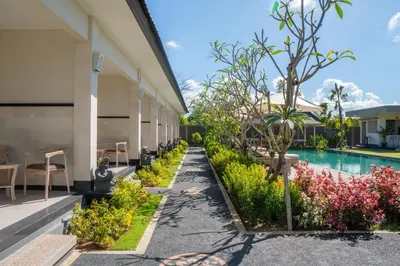 a walkway next to a building with a swimming pool at Green D'mel Bali in Nusa Dua
