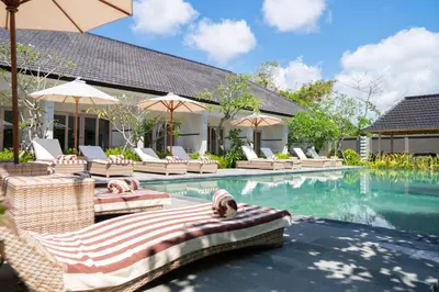 an image of a swimming pool with chairs and umbrellas at Green D'mel Bali in Nusa Dua