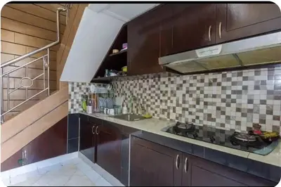 a kitchen with dark wood cabinets and a sink at DENAYS GUESTHOUSE JIMBARAN in Jimbaran