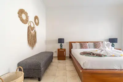 a bedroom with a bed and a ottoman in it at Casa Jinah 2 I Simply Modern Twin Villas (2BR) in Bidadari in Seminyak