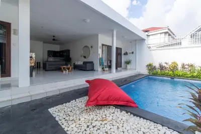 a house with a swimming pool and a red umbrella at Casa Jinah 2 I Simply Modern Twin Villas (2BR) in Bidadari in Seminyak