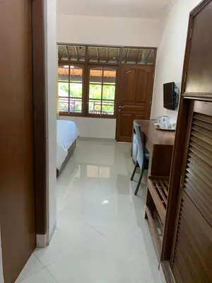 a bedroom with a bed and a desk in a room at Fat Yogi Cottages in Kuta