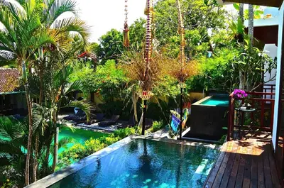 a swimming pool in a garden with trees at Aqua Octaviana Bali Villa in Canggu