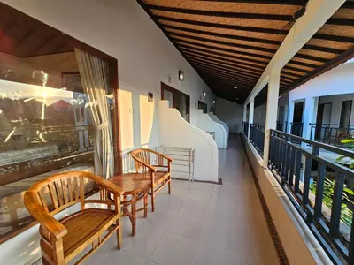 a balcony with two wooden benches and a table at Tegalsari Guest House Canggu in Canggu