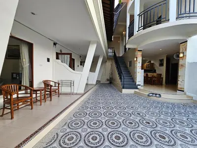 a hallway with a tile floor with chairs and a staircase at Tegalsari Guest House Canggu in Canggu