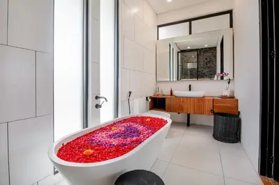 a bathroom with a bath tub covered in red flowers at Villa Giraffe Seminyak, 4br short walk to Potato Head in Seminyak
